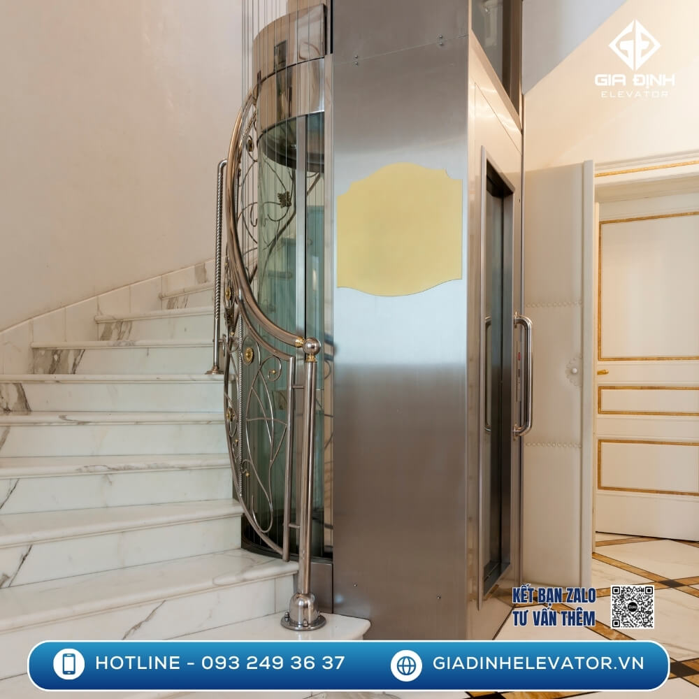 Thang máy mini hình trụ lắp giữa cầu thang xoắn nhà phố, thiết kế bo tròn mềm mại, tiết kiệm diện tích. Giá thang máy mini